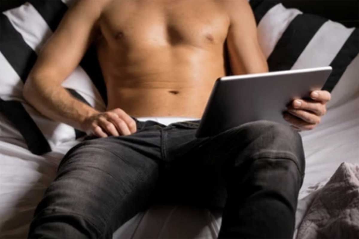 image homme dans un lit torse nue avec une tablette